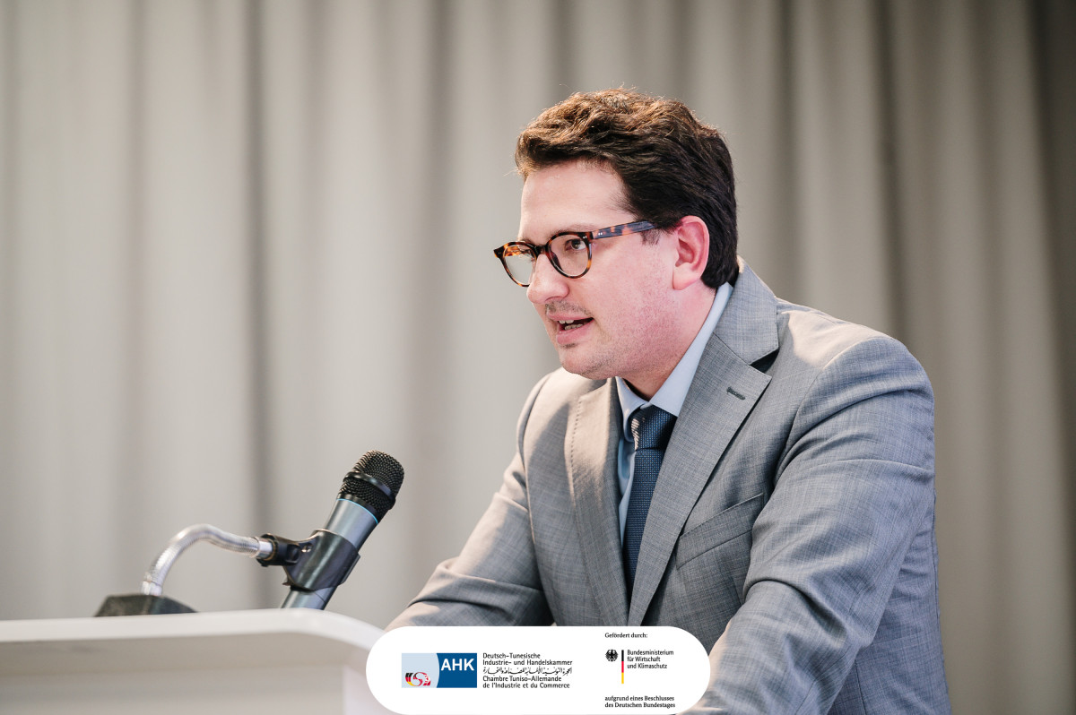 Bastian Mahmoodi spricht am Rednerpult der Deutsch-Tunesischen Industrie- und Handelskammer in Tunis.