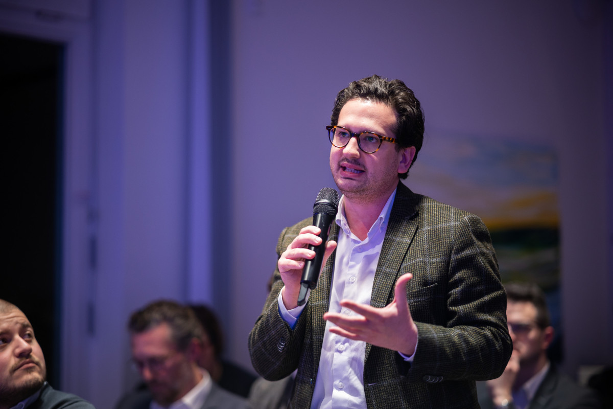 Bastian Mahmoodi stellt eine Frage mit Mikrofon während einer Diskussion oder Konferenz.