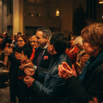 Publikum applaudiert bei einer Veranstaltung in einer Kirche.